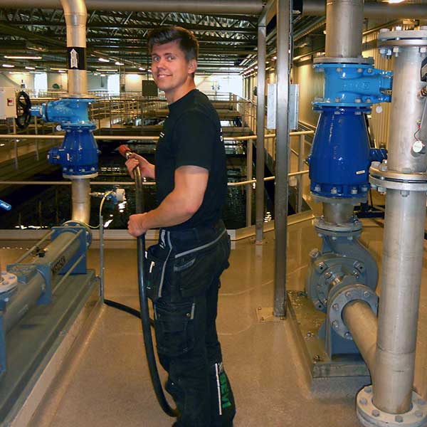 En man står i ett reningsverk och gör service på en pumpmotor.